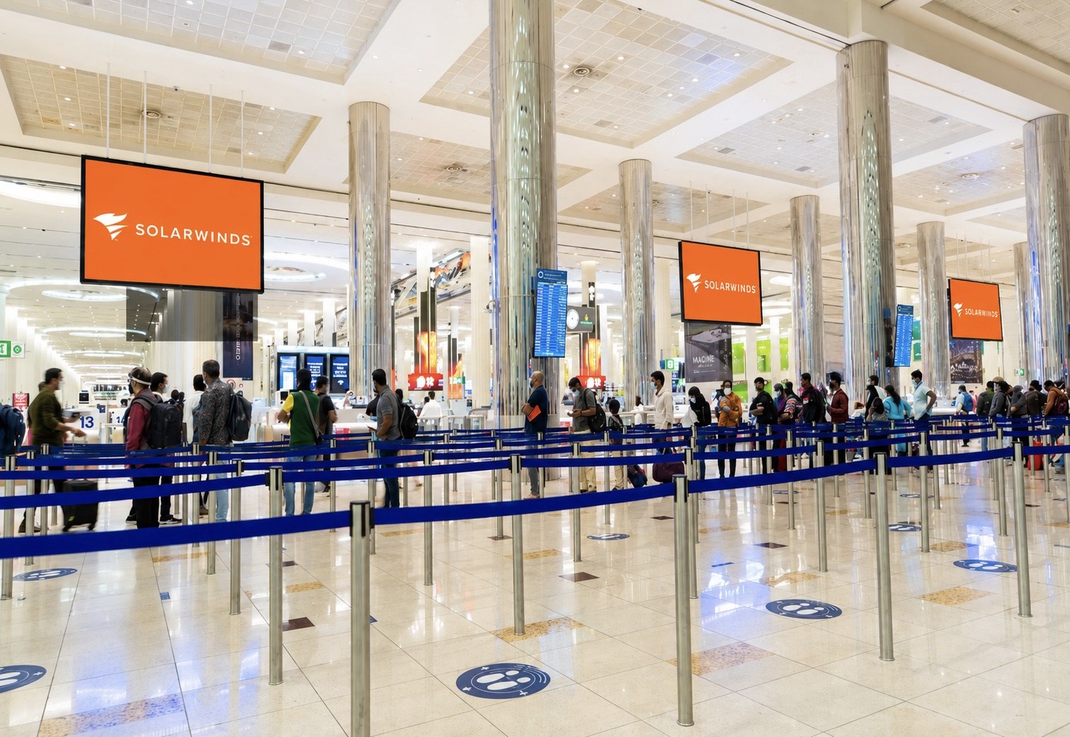 Three SolarWinds digital LED screens above the passport control queues at Dubai International Terminal 3 arrivals